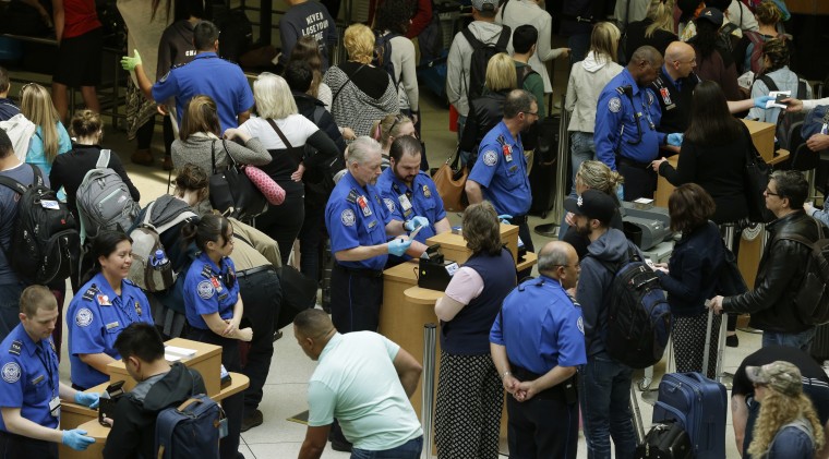 Image: TSA agents check passenger boarding passes and identification at a security screening checkpoint