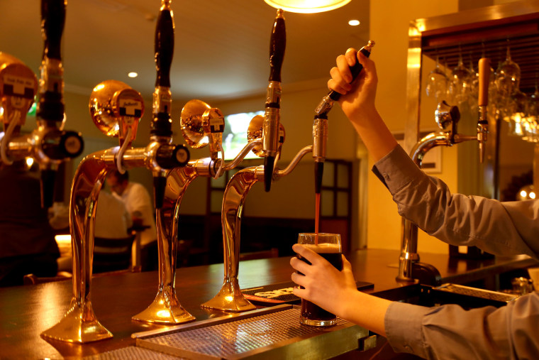 Image: A woman pours a pint of Guinness in a pub in Dublin, Ireland