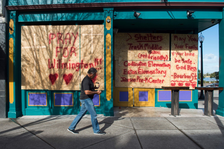 Image: A man walks past a boarded up shop in Wilmington, North Carolina