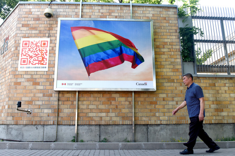 A man walks past a poster of a rainbow flag outside the Canadian embassy in Beijing on May 18, 2018.