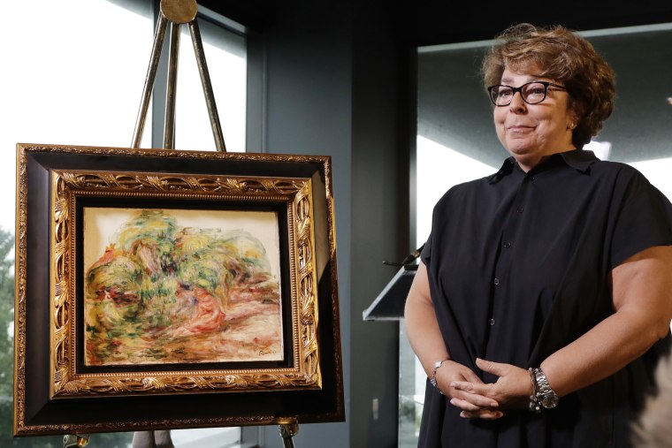 Image: Sylvie Sulitzer, a delicatessen owner from the south of France, stands with a Renoir painting that was returned to her in a reparation ceremony at a news conference on Sept. 12, 2018, in New York.