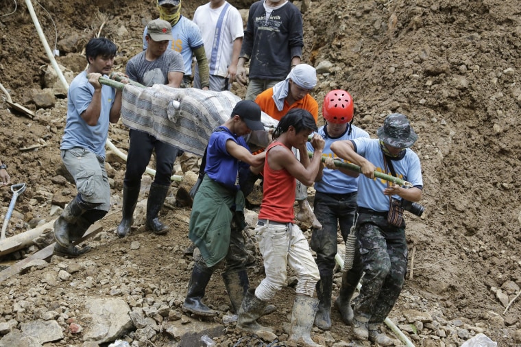 Image: Rescuers carry a body from the site where victims are believed to have been buried by a landslide