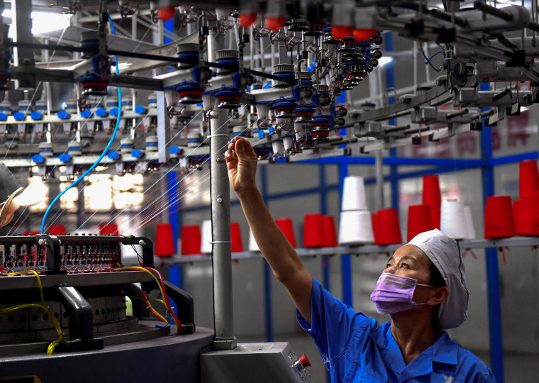Image: An employee monitors a circular weaving machine at a textile factory in Shangqiu, China