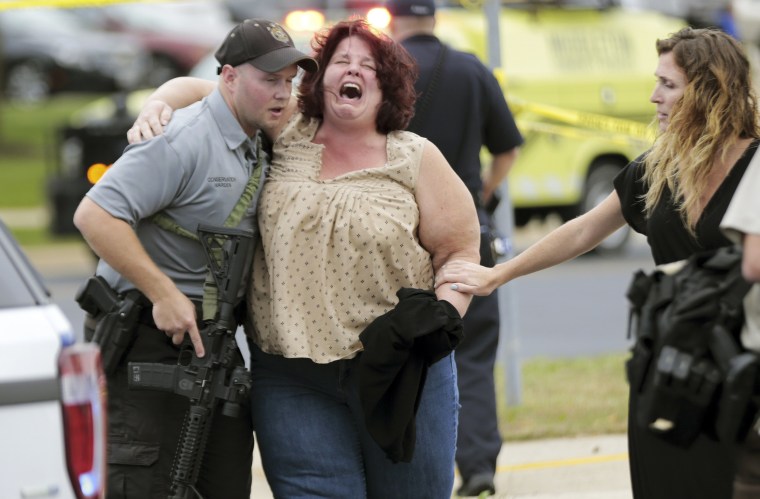Image: A women is escorted from the scene of a shooting at a software company in Middleton, Wis.