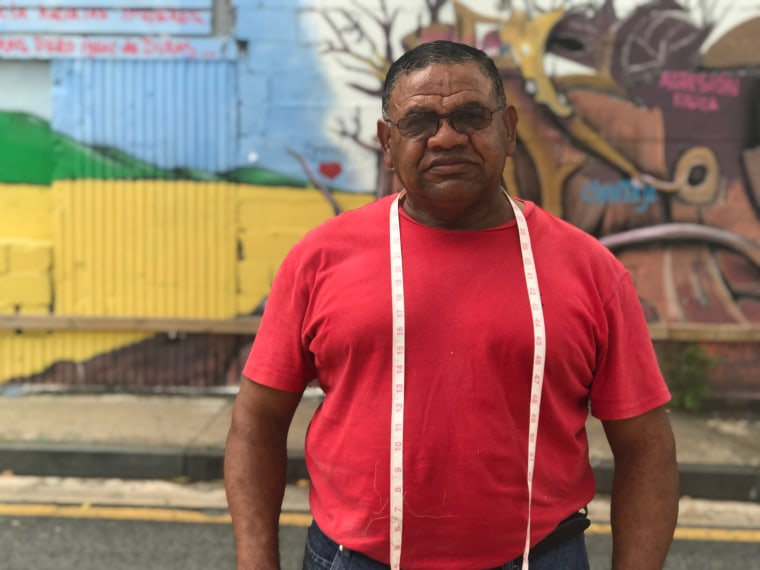 Porfirio "Pachin" Guerrero, who's worked as a tailor for more than 30 years, poses in front of a mural in Rio Piedras, Puerto Rico.