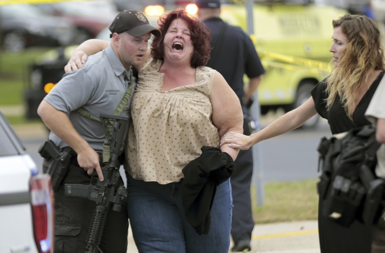 Image: A women is escorted from the scene of a shooting at a software company in Middleton, Wis.