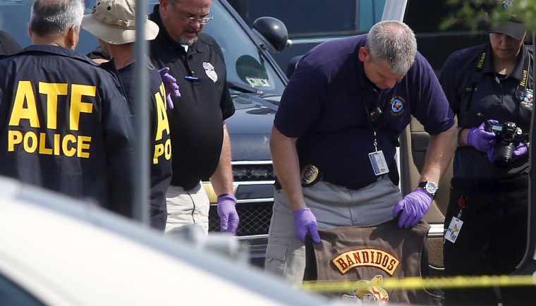 Image: A police officer removes a jacket bearing the name of the Bandidos motorcycle gang from a vehicle at the Twin Peaks restaurant in Waco