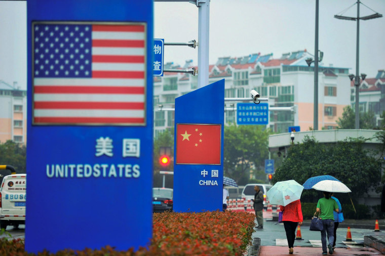 Image: Signs featuring U.S. and Chinese flags are seen outside a store selling foreign goods in Qingdao, China