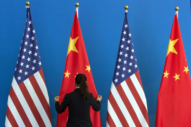 Image: A woman adjusts the Chinese national flag near U.S. national flags