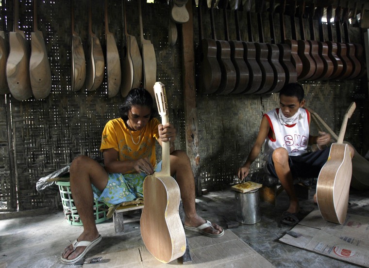 Image: Workers assemble guitars at a private gu