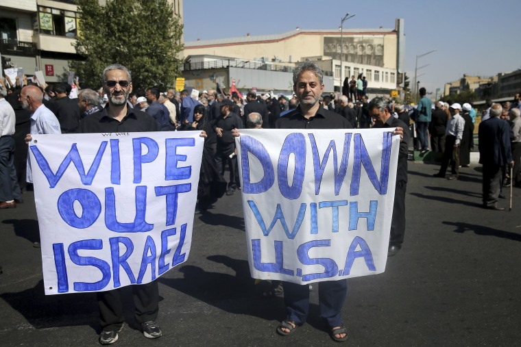 Image: Men hold up anti-American and anti-Israeli placards at a rally condemning the attack in Ahvaz 