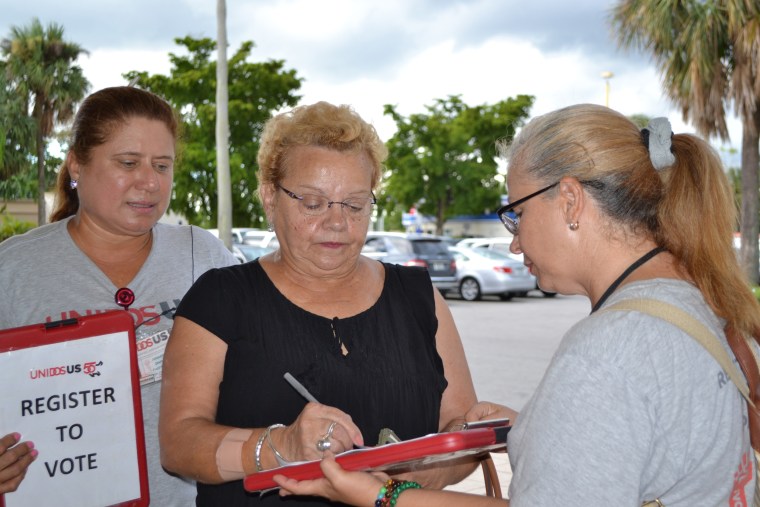 Volunteers from the non-partisan group, UnidosUS, register people to vote outside a Sedano's supermarket in Miami's 26th congressional district