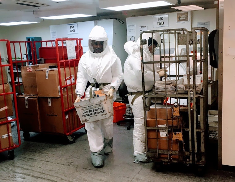 U.S. Defense Department personnel, wearing protective suits, screen mail as it arrives at the Pentagon