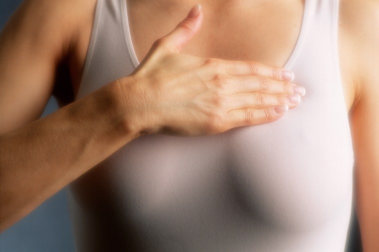 Woman examining breast, mid-section, close-up