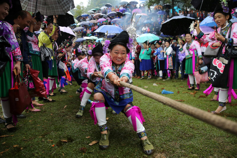 Image: Ethnic Miao women in traditional costumes take part in a tug of war to celebrate a local festival at a village in Rongshui Miao Autonomous County