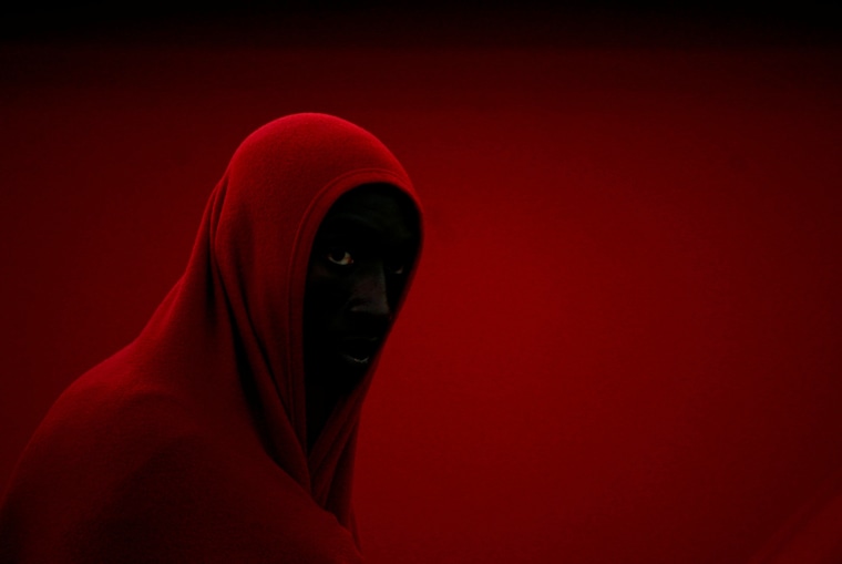 Image: A migrant, part of a group intercepted off the coast in the Mediterranean Sea, stands in a queue after arriving on a rescue boat at the port of Motril