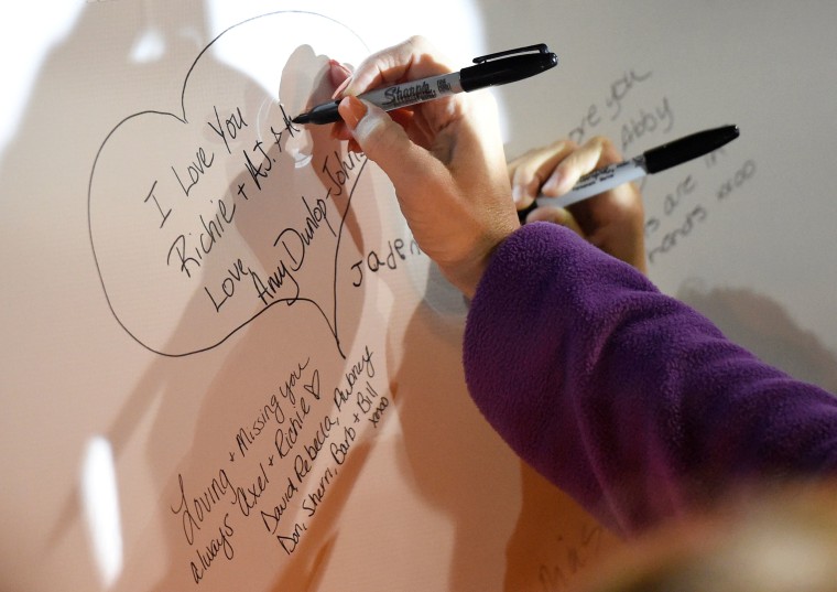 Image: Family members sign a banner in memory of their loved ones during a candlelight vigil for the victims of a limousine accident in upstate New York in Amsterdam
