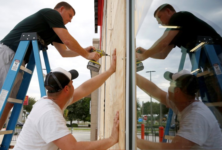 Image: Justin Davis, left, and Brock Mclean board up a business in advance of Hurricane Michael in Destin