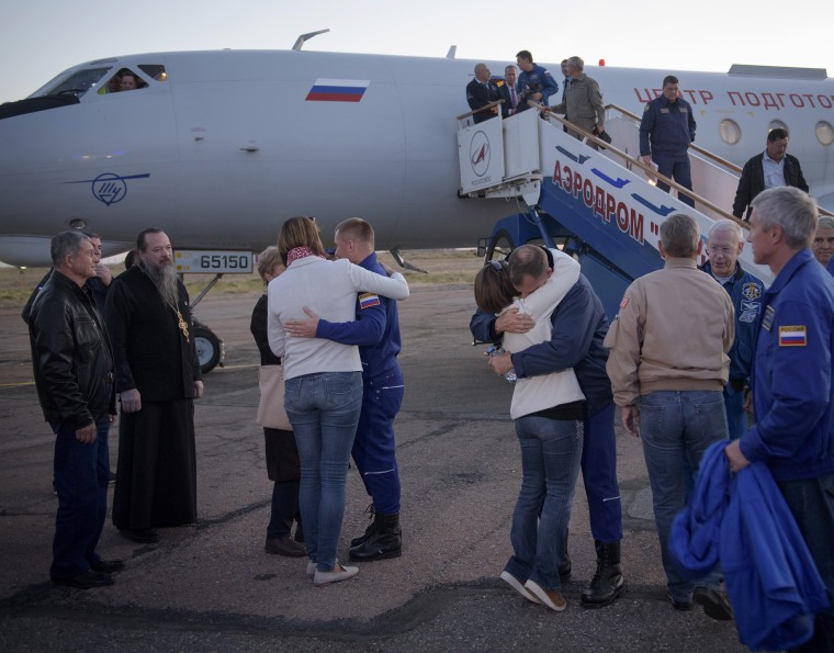 Cosmonaut Alexey Ovchinin, left, and NASA's Nick Hague, right, hug their families after landing at Baikonur Cosmodrome in Kazakhstan.