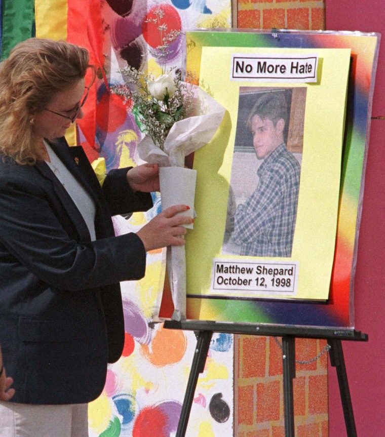 Kate Keating places flowers on the picture of Matthew Shepard during a memorial in Denver Oct. 12, 1998.