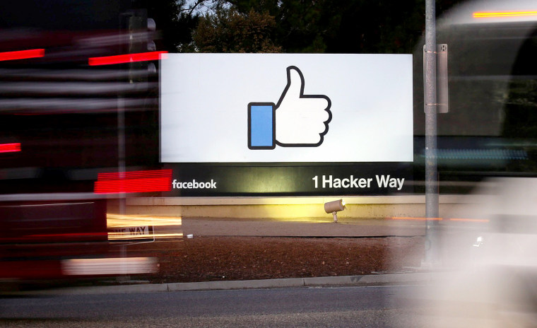 Image: The entrance sign to Facebook headquarters is seen through two moving buses in Menlo Park