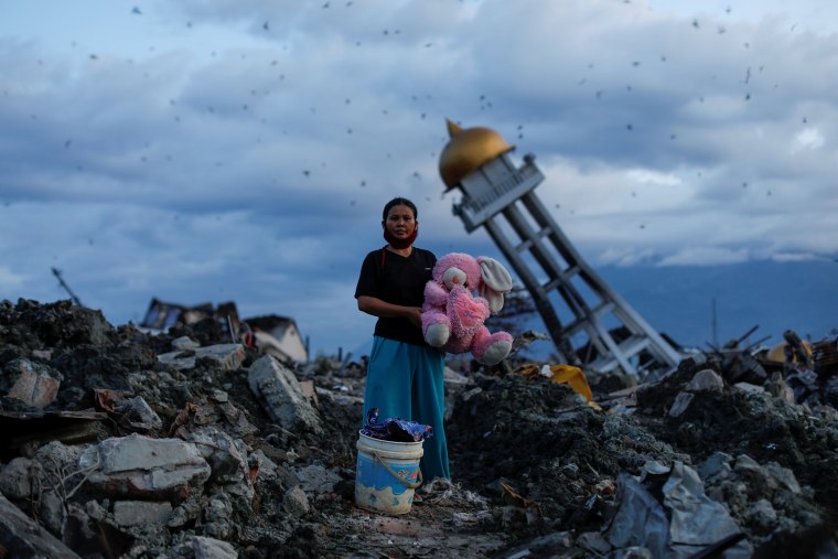 A woman holds a stuffed rabbit toy after it was found at her destroyed home where she said she had lost her three children, in Palu