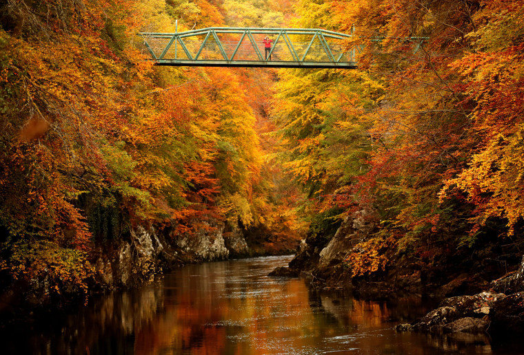 A woman stands on the footbridge over the river Garry near Pitlochry , Scotland