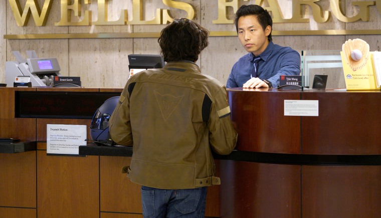 Bank Teller Tyler Wong talks to a customer at the Wells Fargo bank in Denver on April 13, 2016.