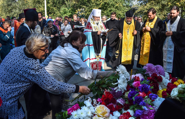 Image: People lay flowers for the victims during a church service in Kerch, Crimea