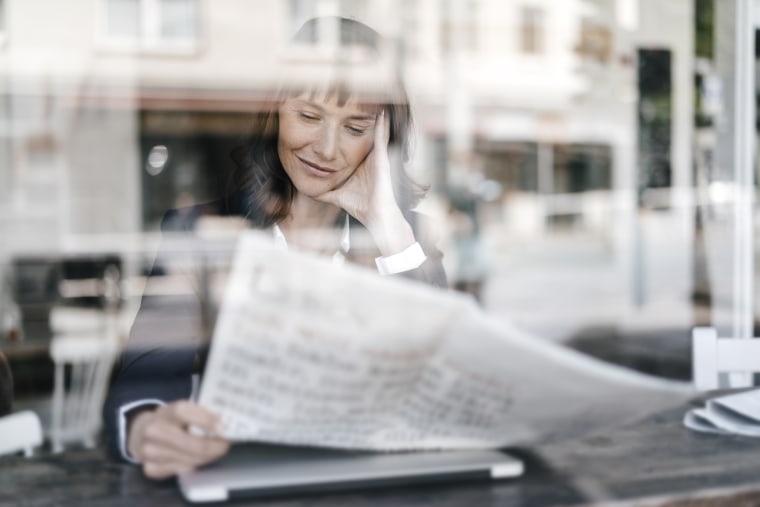 Businesswoman sitting cafe, reading newspaper