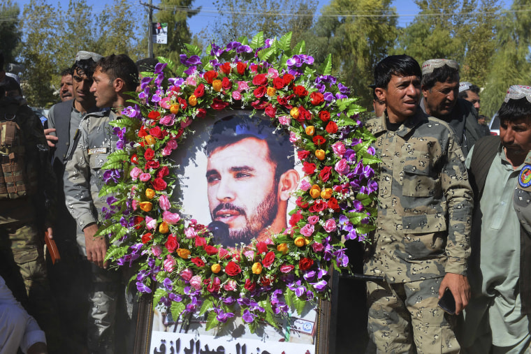 Image: Military personnel hold a photo of Gen. Abdul Raziq, Kandahar police chief, who was killed by a guard, during his burial ceremony in Kandahar