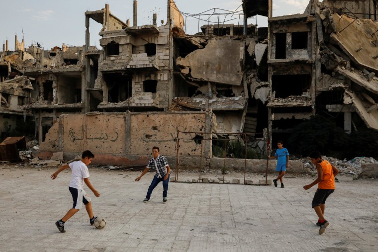 Image: Children play soccer in a government-controlled part of Homs