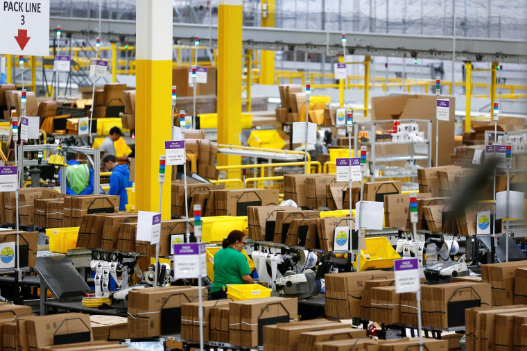 Image: Employees work at pack stations at the Amazon fulfillment center in Kent