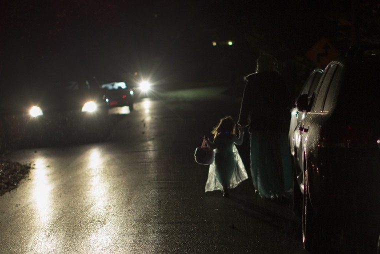 A little girl in an Elsa costume walks with her mother in a light rain as they go trick or treating on Halloween night in the New York City suburb of Valley Cottage, New York