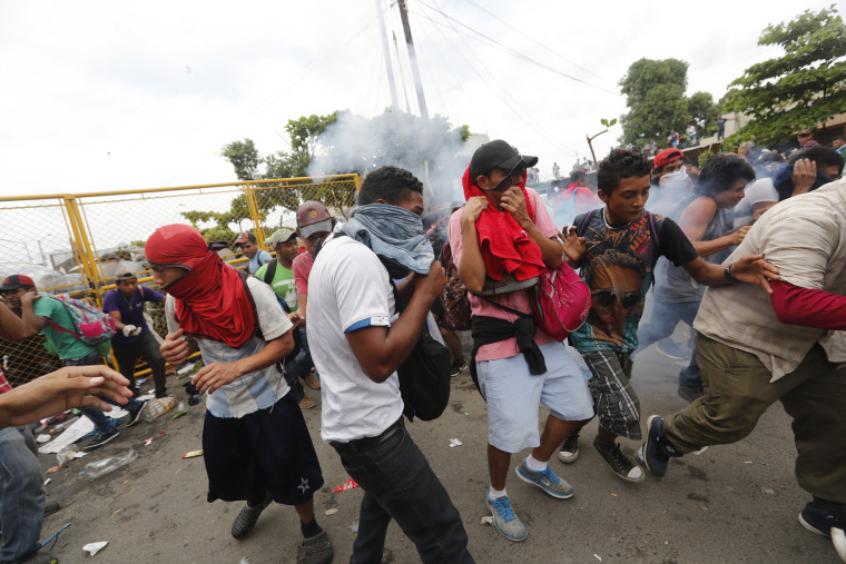 Image: Migrants break the fence between Guatemala and Mexico and fight police