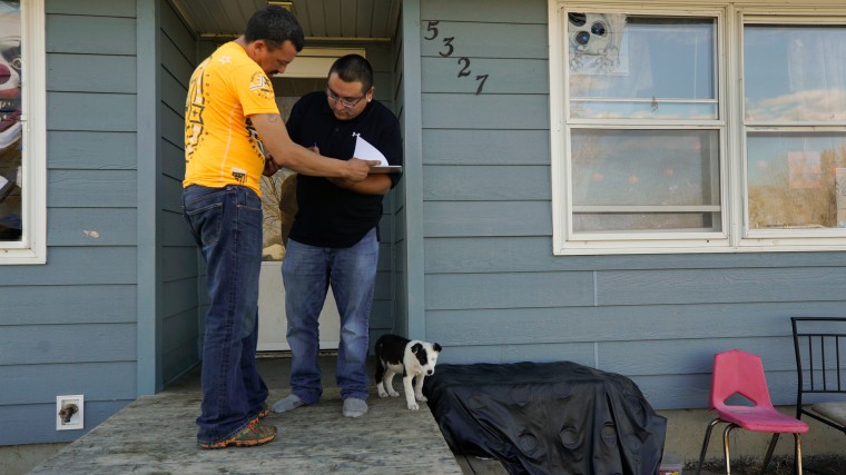 Jesse McCloud helps Whitney Agard Whitebull fill out voter ID information at his home on the Standing Rock Reservation in Fort Yates, N.D.