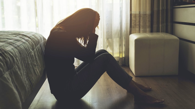 Image: depressed woman sitting in the dark bedroom