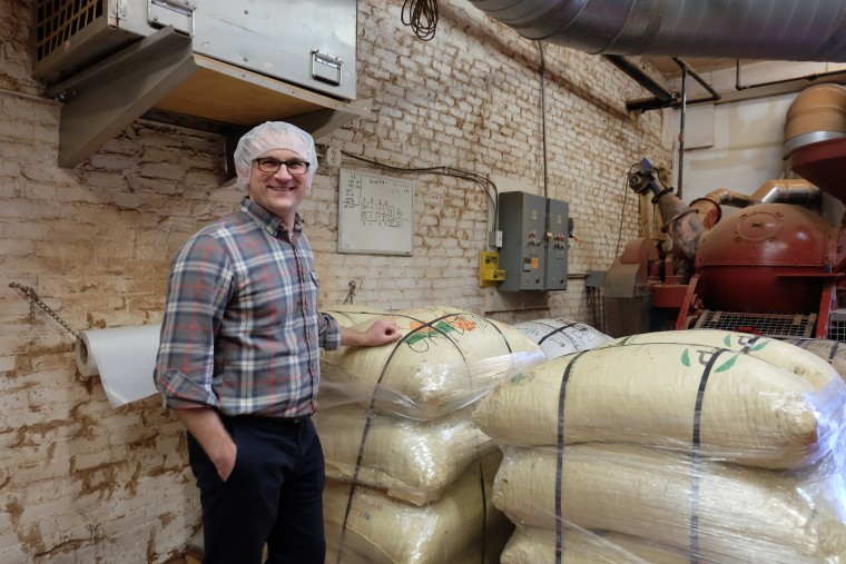 Jesse Last, Taza's sourcing manager, stands in front of bagged beans from different countries