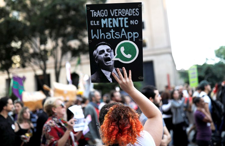 Image: A woman holds a sign with an image of presidential candidate Jair Bolsonaro during a protest in Sao Paulo