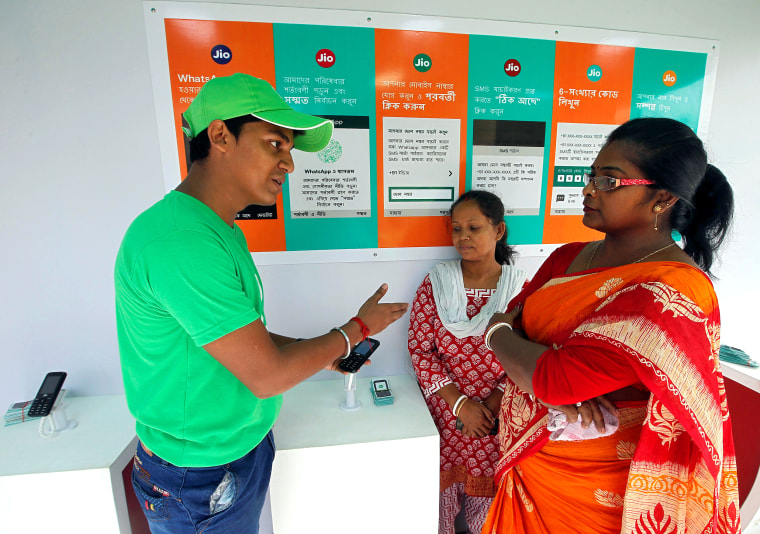 A WhatsApp-Reliance Jio representative explains how to use Facebook Inc's WhatsApp messenger to a woman during a drive by the two companies to educate users, on the outskirts of Kolkata