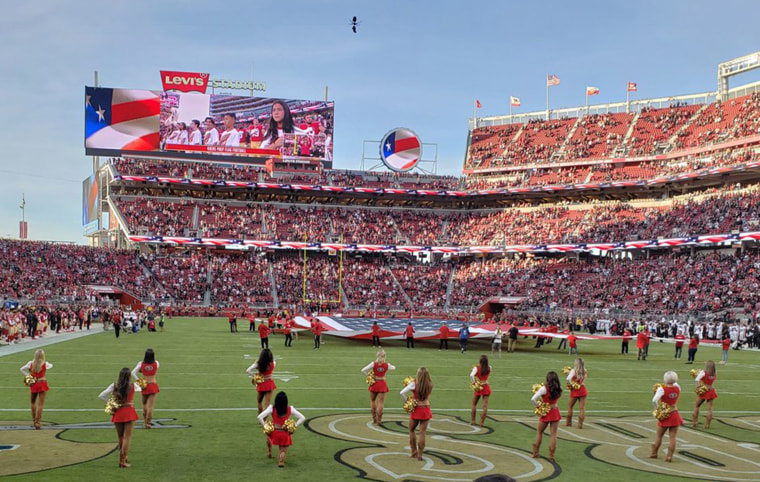 Image: A San Francisco 49ers cheerleader kneels during the national anthem
