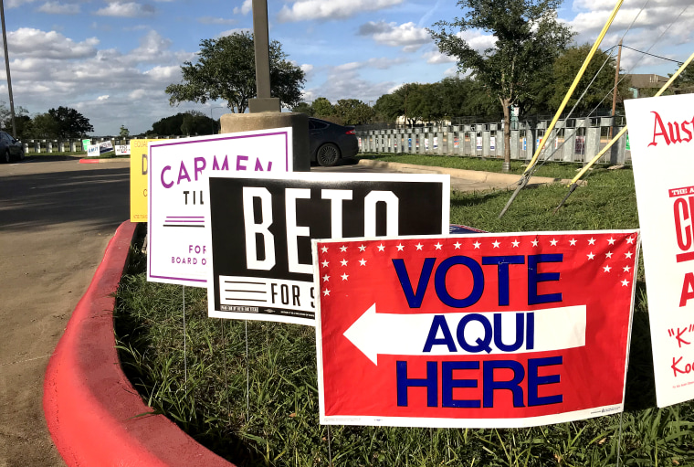A Spanish-language sign directs voters to an early voting polling location in east Austin, in front of a campaign sign for Beto O'Rourke, a Democratic candidate for U.S. Senate.
