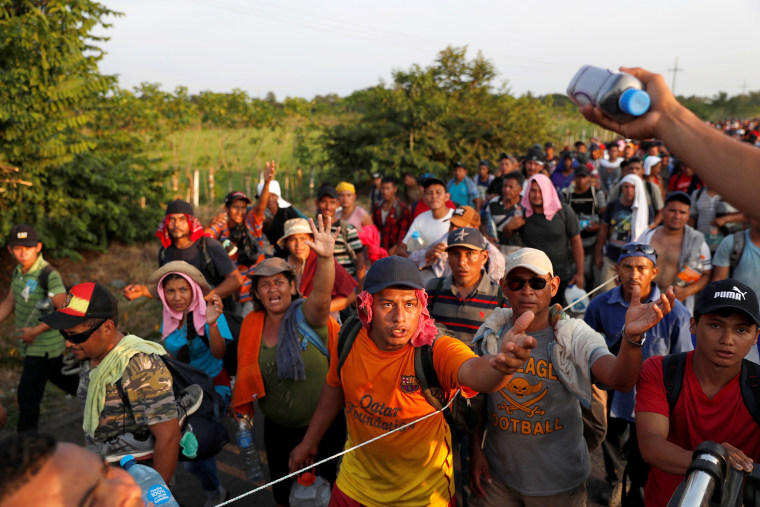 Image: Migrants, part of a caravan traveling from Central America en route to the United States walk by the road that links Ciudad Hidalgo with Tapachula