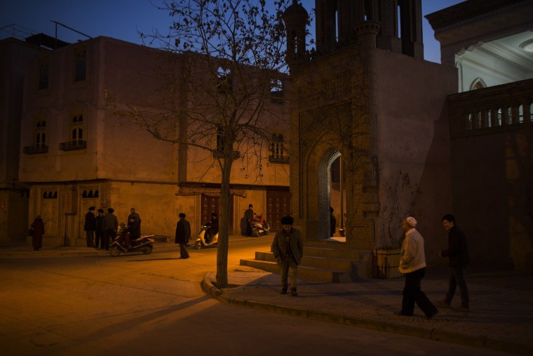 Image: Men congregate outside a mosque in the old city in Kashgar, Xinjiang.