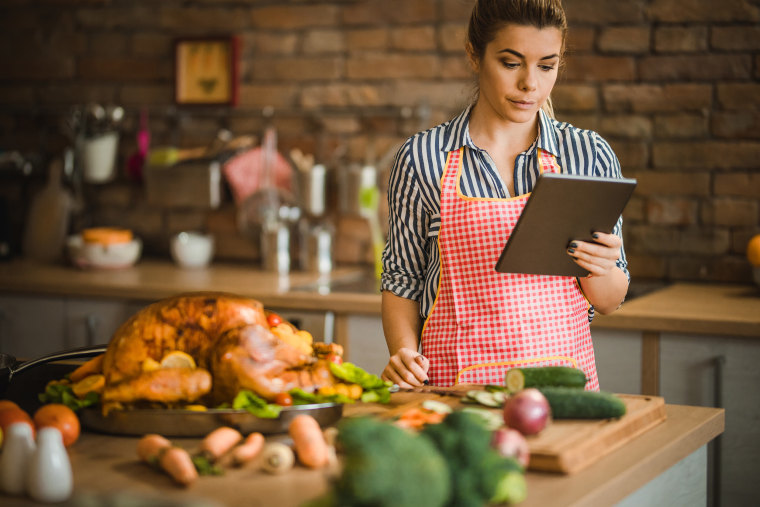 Young woman using digital tablet on Thanksgiving day in the kitchen.