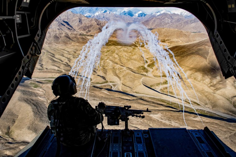 Image: A U.S. Army crew chief flying on board a Chinook helicopter observes the successful test of flares during a training flight in Afghanistan