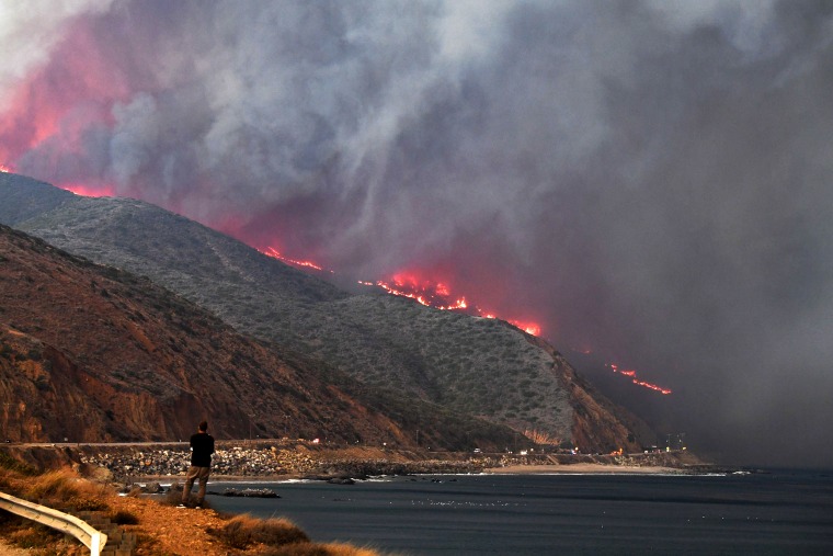 Image: A man watches as the Woolsey Fire reaches the ocean along Pacific Coast Highway (Highway 1) near Malibu, California, Nov. 9, 2018