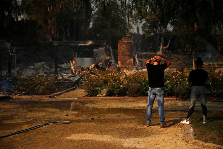 Alexander Tabolsky and Dina Arias look at the destroyed home they lived in as the Woolsey Fire continues to burn in Malibu, California on Nov. 10, 2018.