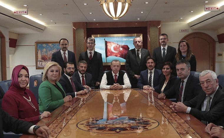 Image: Turkish President Recep Tayyip Erdogan poses for photos with Turkish journalists aboard his plane