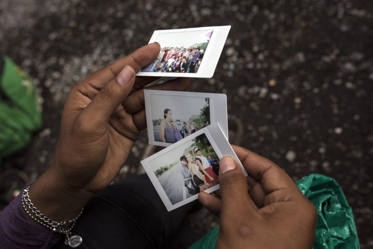 A member of the group looks at polaroid photos documenting their journey on the road to Sayula, Mexico, on Nov. 3, 2018.